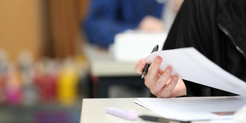 Australian student writing on an exam paper (Photo by Lincoln Beddoe/iStock)